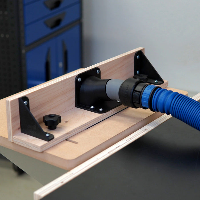 Workbench with a router table and QuickFence with the Rockler vacuum hose attached in a workshop setting.