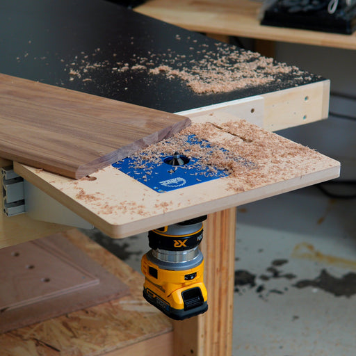 Woodworking router table with a piece of wood being routed on a workshop bench.
